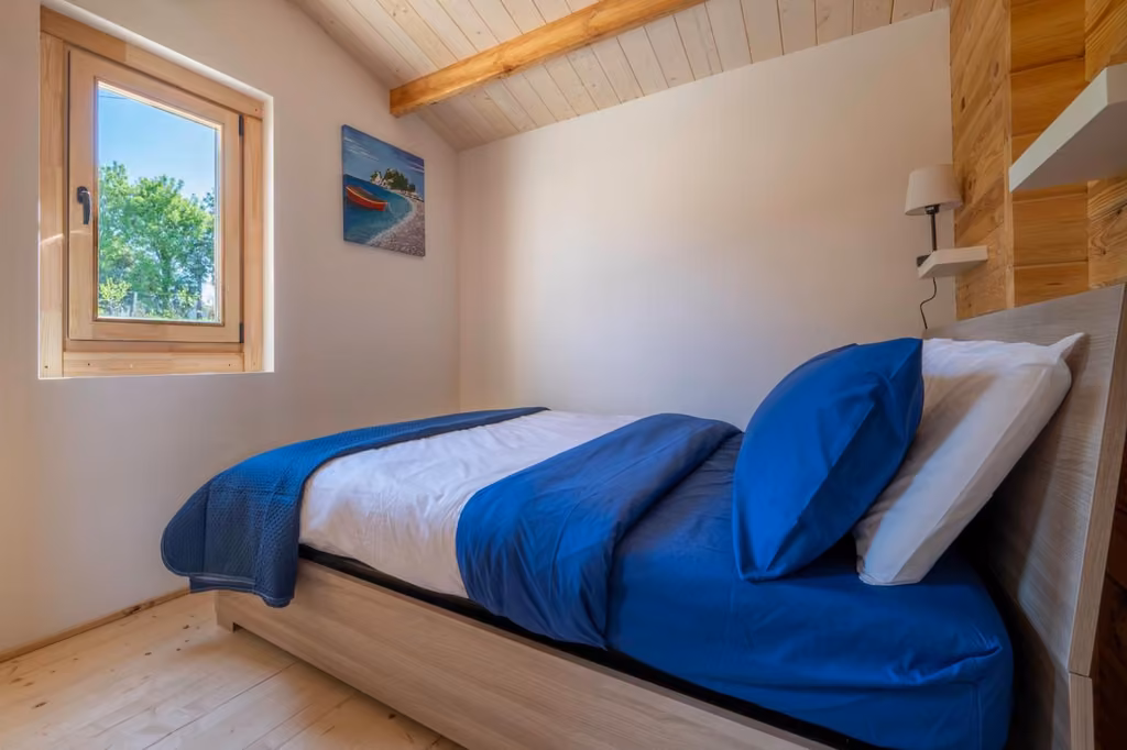 Camera da letto con letto matrimoniale e lenzuola blu, finestra con vista sulla campagna di Atessa